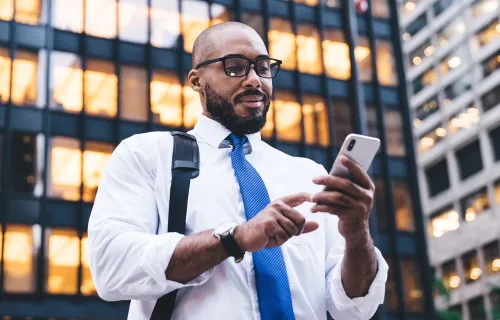 person using mobile phone in front of office building