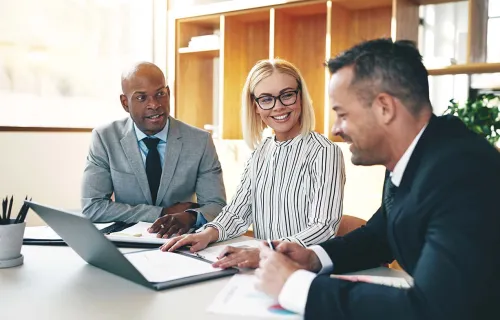 Trois professionnels se réunissent à un bureau devant un ordinateur portable