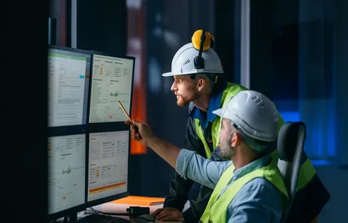 two engineers analyzing data on multiple monitors