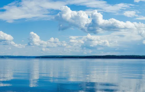 Kama River, darüber blauer Himmel mit Wolken, die sich im Wasser spiegeln