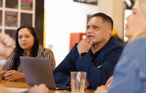 People sitting at a table listening to a speaker