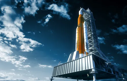 A rocket on a launch pad with blue sky and clouds in background