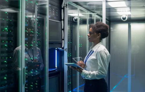 Consultant with tablet inside a data center reviewing cybersecurity risks