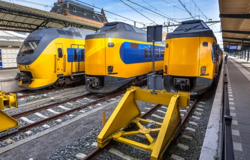 Trois trains jaunes et bleus en attente dans une gare