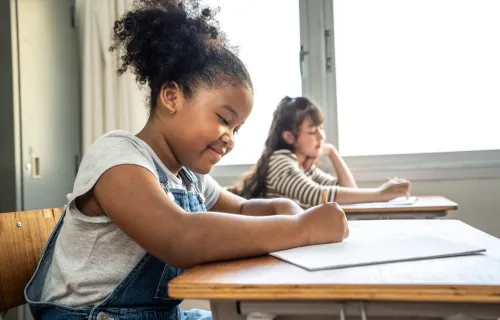 Two children sitting at desks in a classroom