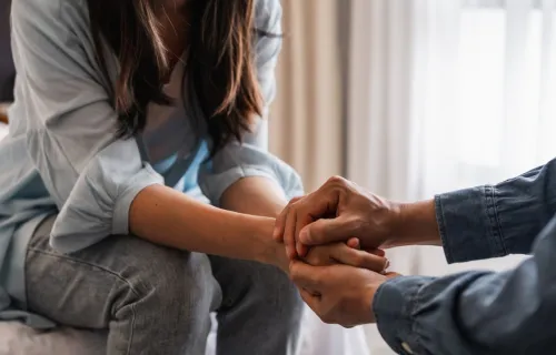 Two people holding hands to comfort each other