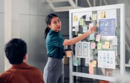 UX consultant sticking sticky note to kanban board