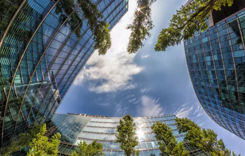 view of sky surrounded by glass skyscraper and trees