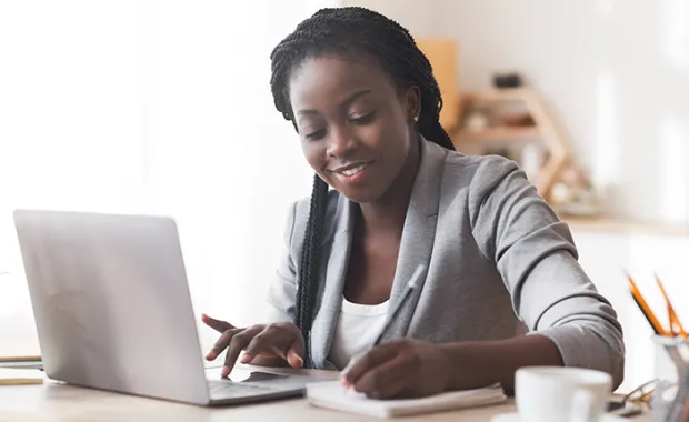 Businesswoman working in office, typing on laptop and taking notes