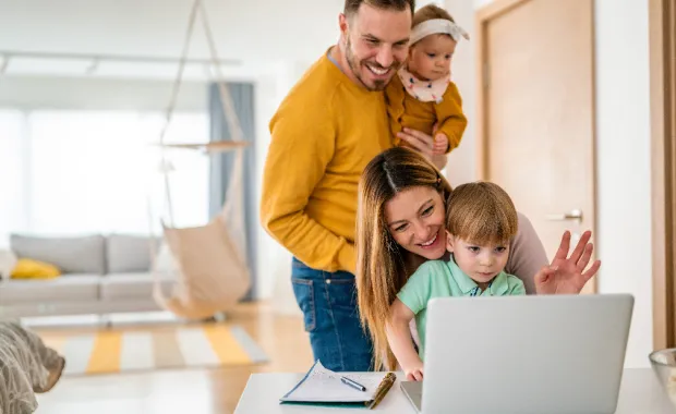 Kuvituskuvassa: Onnellinen perhe kotona tietokoneen ääressä