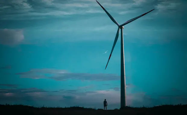 skyline with wind turbine with a person standing next to it