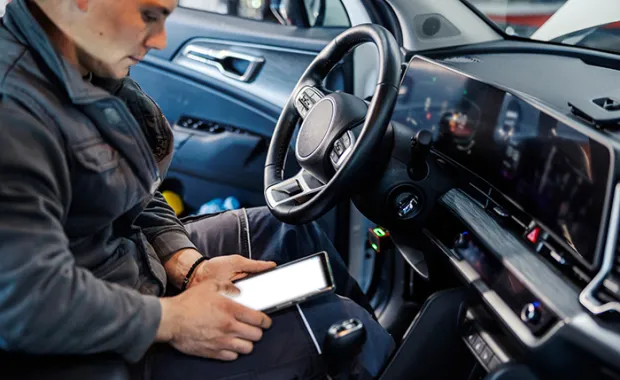 a police officer sitting in a vehicle looking at a tablet 