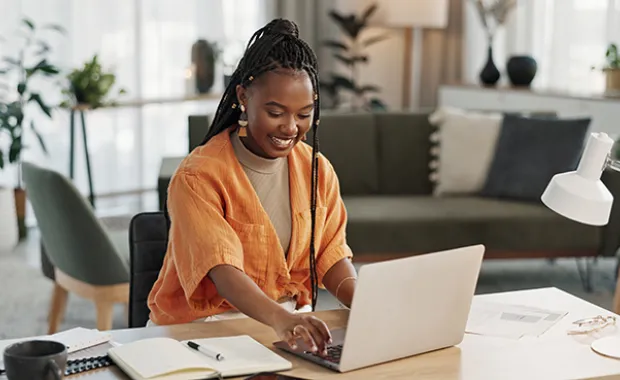 A woman sitting at a desk and looking at a computer smiling 