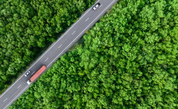 aerial view of a car and truck driving on highway road through a forest