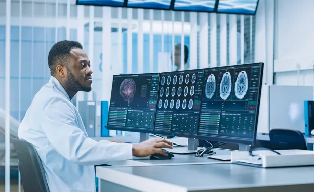 Manlig doktor tittar på röntgenbilder på tre stora skärmar