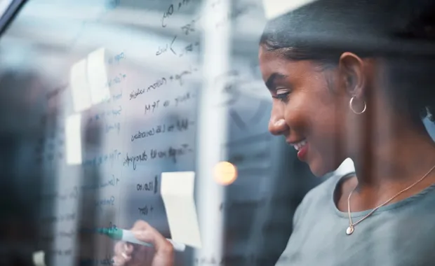 Junge Frau schreibt etwas auf ein Whiteboard aus Glas