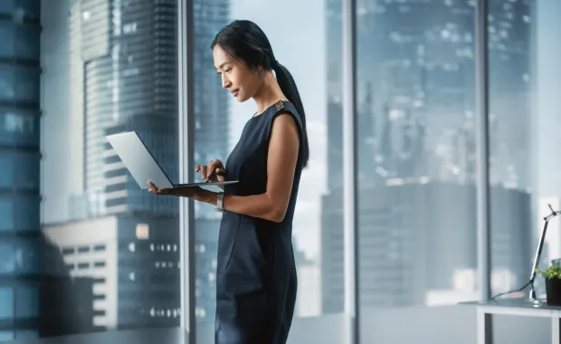 executive viewing a laptop in a boardroom in front of a window