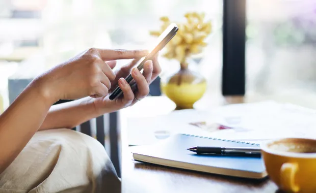 Person sitting at table, holding mobile phone