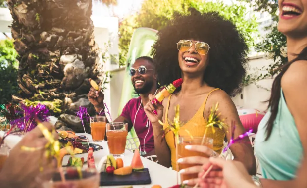 Eine Outdoor-Party mit fröhlichen Gästen, in der Mitte eine glücklich lachende Frau