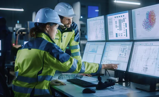 two engineers in hard hats examine artificial intelligence data