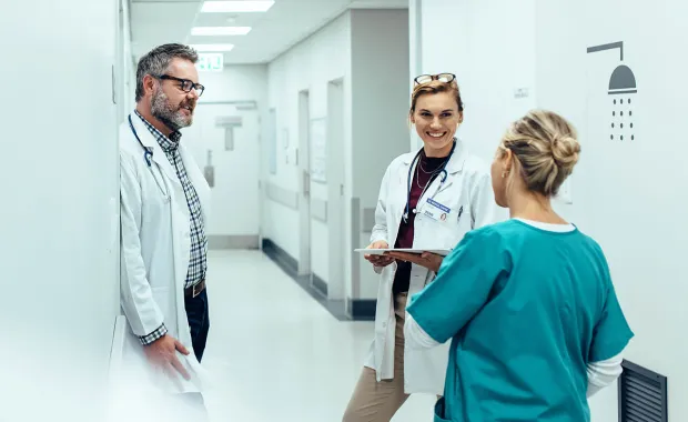 två läkare och en kirurg samtalal i en sjukhuskorridor