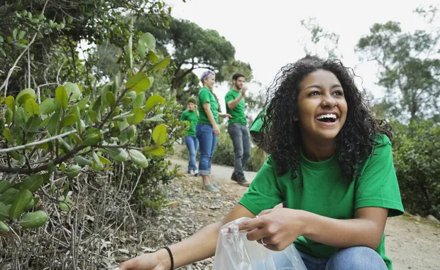 Women in green tshirt smiling picking up litter