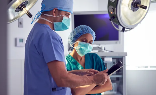 Två kirurger tittar på en surfplatta i sjukhusets operationsrum.