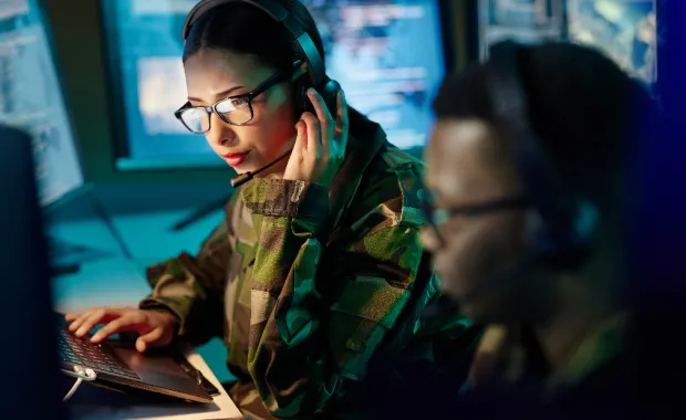 Two military personnel working in front of computer screens