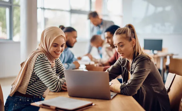 multicultural professionals reviewing content on a laptop device