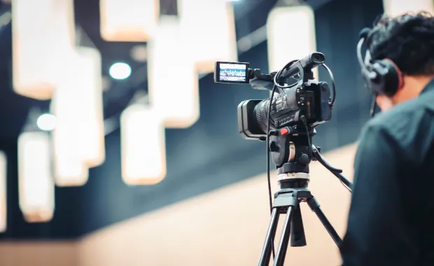 Person wearing headphones standing behind camera