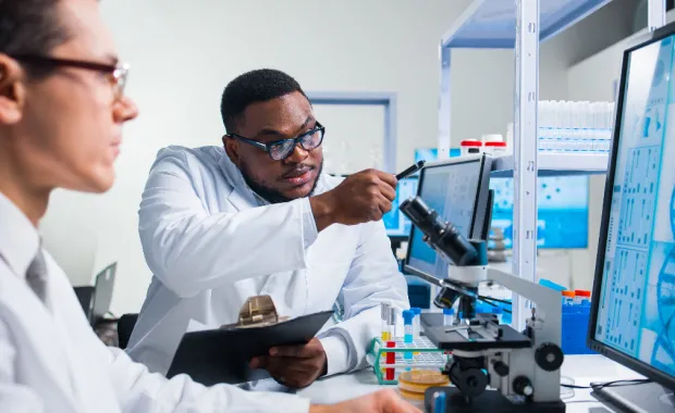 Deux professionnels étudient un rapport scientifique sur un écran d’ordinateur dans un laboratoire médical