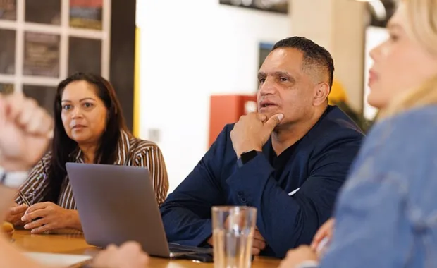 People sitting at a table listening to a speaker