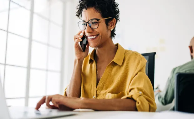 Smiling woman using mobile phone and laptop