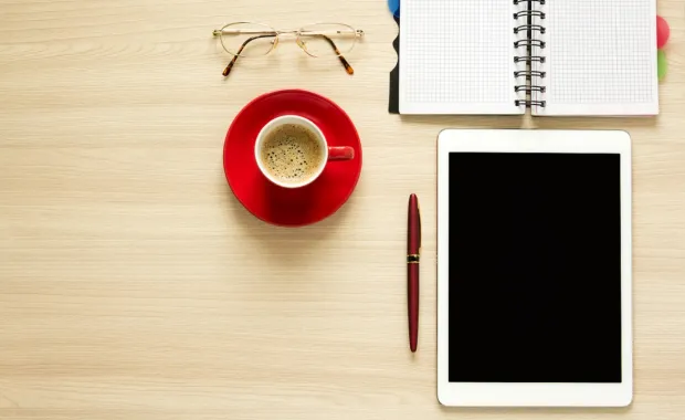 coffee, tablet, pen & paper pad on a desktop
