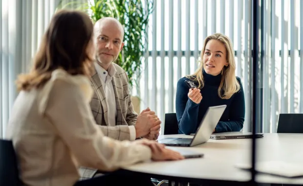 Three colleagues meeting in a conference room at the office