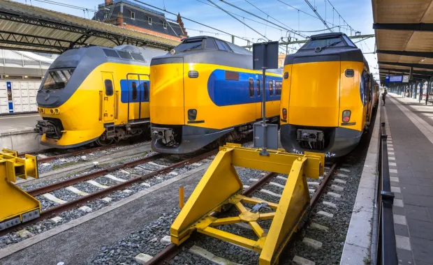 Three yellow and blue trains waiting at a station