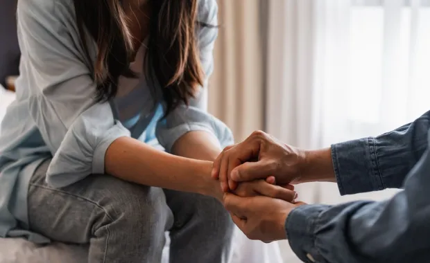 Two people holding hands to comfort each other