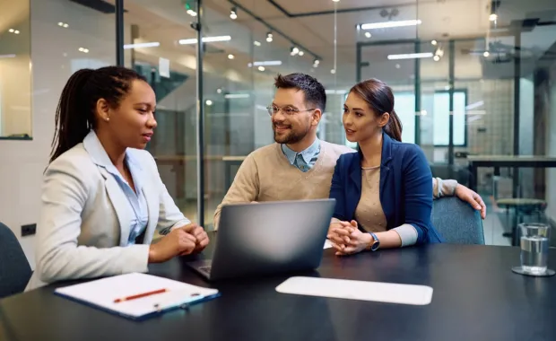 Drei Personen sitzen in einem Besprechungsraum und diskutieren über die neusten Ergebnisse der CGI Voice of Our Client Studie