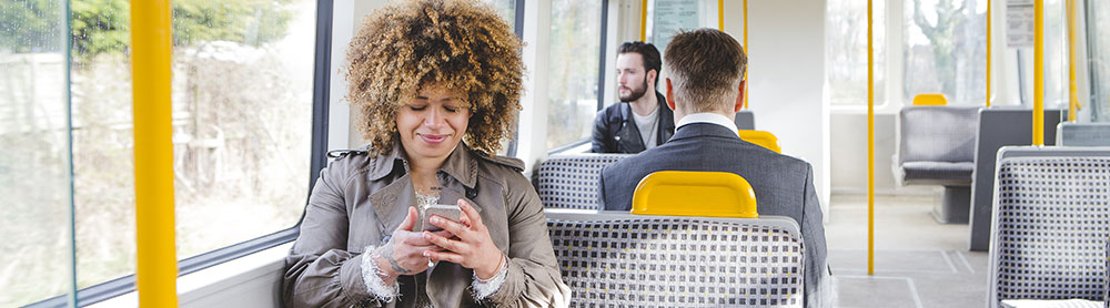 Woman sits on train looking at mobile phone