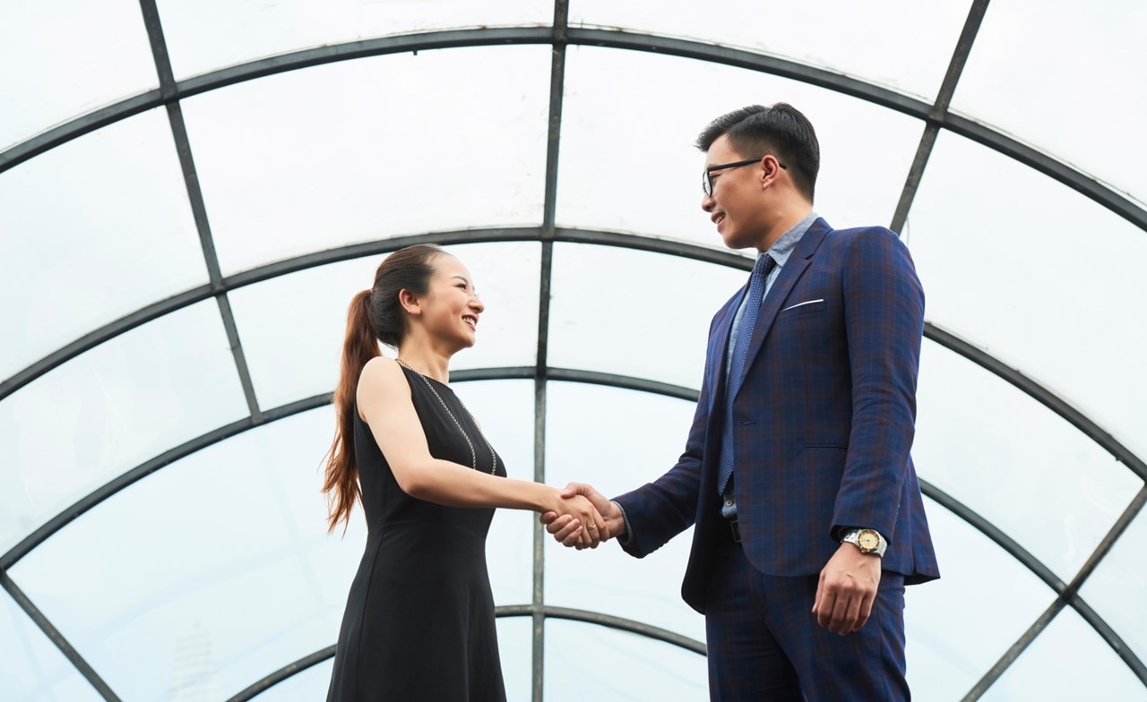 Two people shaking hands in an office corridor