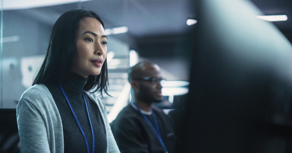 Two professionals working in front of computer screens