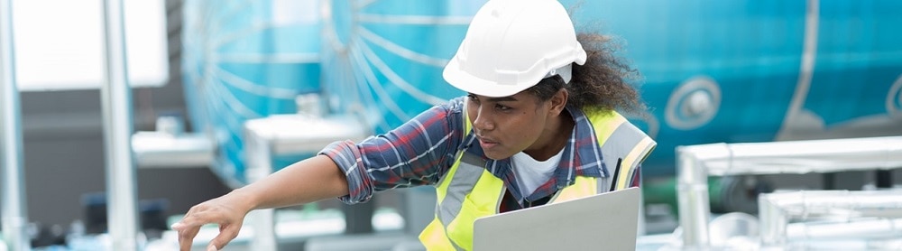 Utility worker holding a computer inspecting equipment